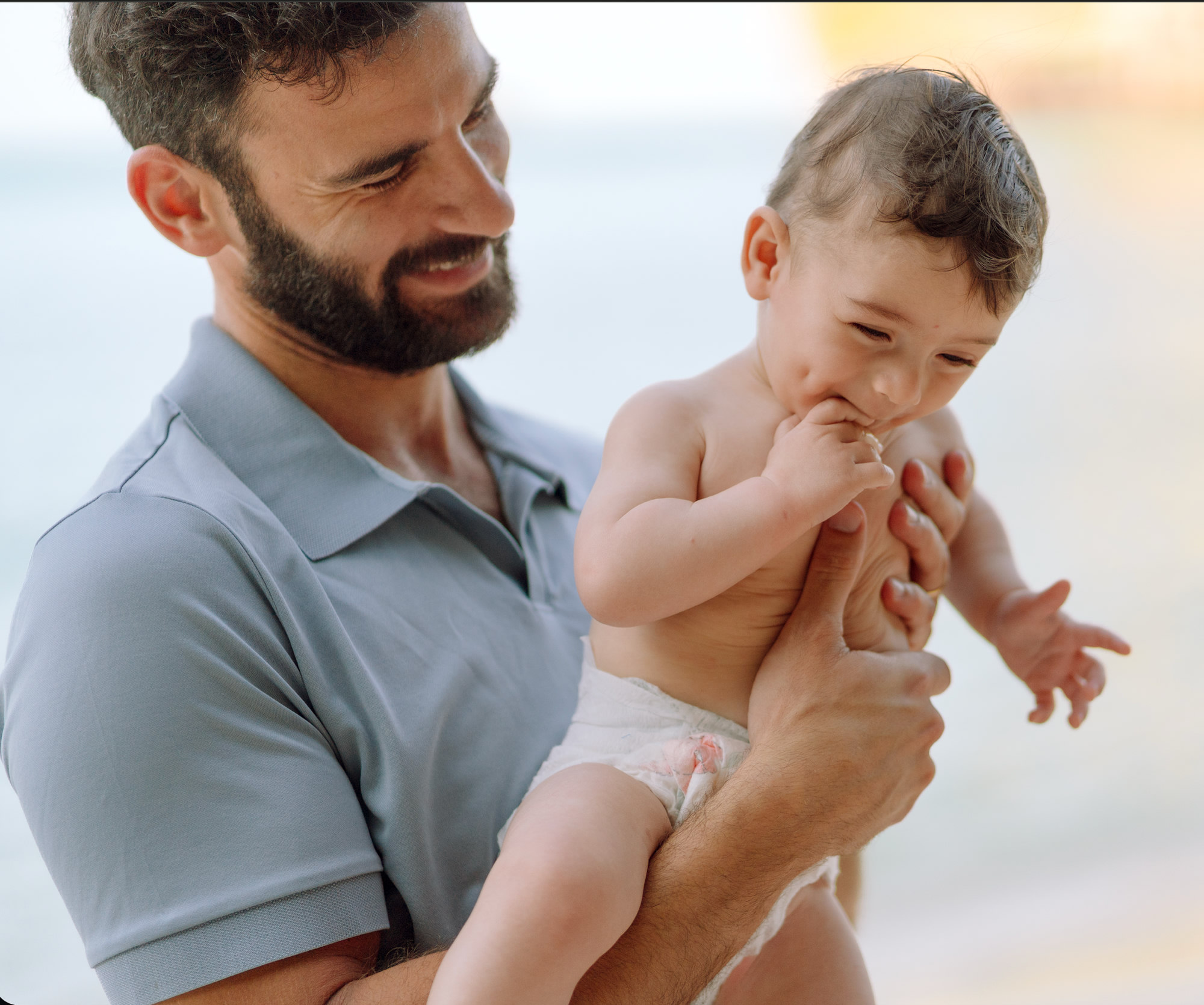 Hagai Mozes holding his son Ethan on a beach at golden hour.